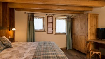 Un dormitorio acogedor con una cama, un escritorio, un televisor y paredes de madera.