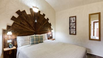 A bedroom with a large bed, wooden headboard, bedside tables, and wall-mounted lights.