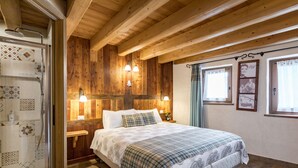 Un dormitorio con paneles de madera, una cama, lámparas de noche y una zona de ducha.