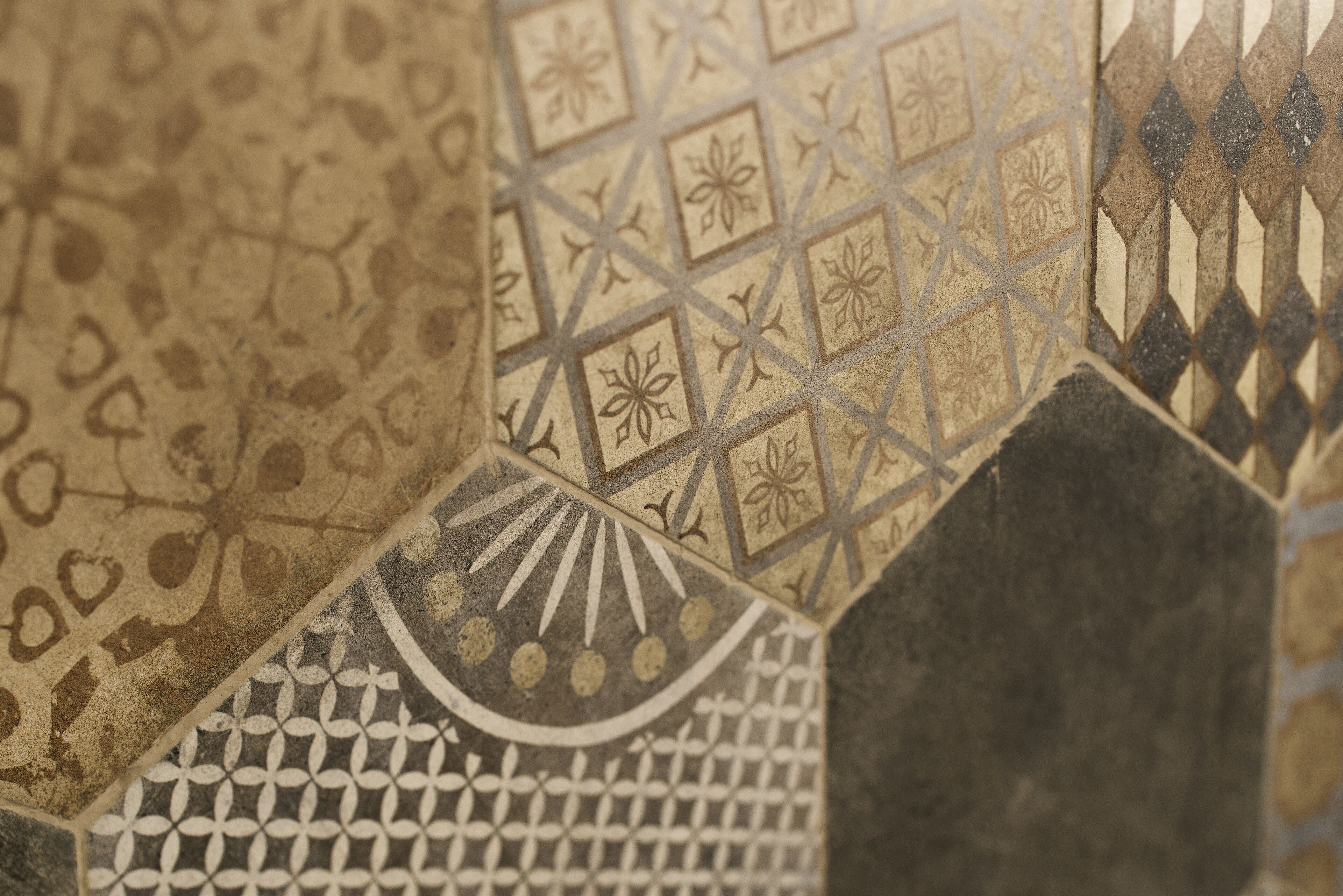 A close-up of a mosaic tile wall with geometric patterns and floral designs.