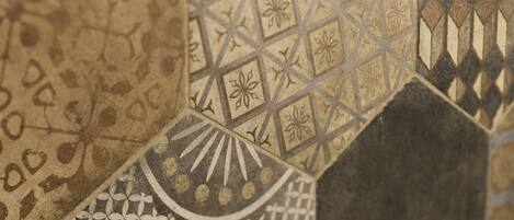 A close-up of a mosaic tile wall with geometric patterns and floral designs.