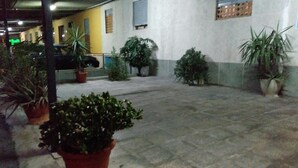 A courtyard with potted plants and a building in the background. - Hostal Mari Loli (San Fulgencio)