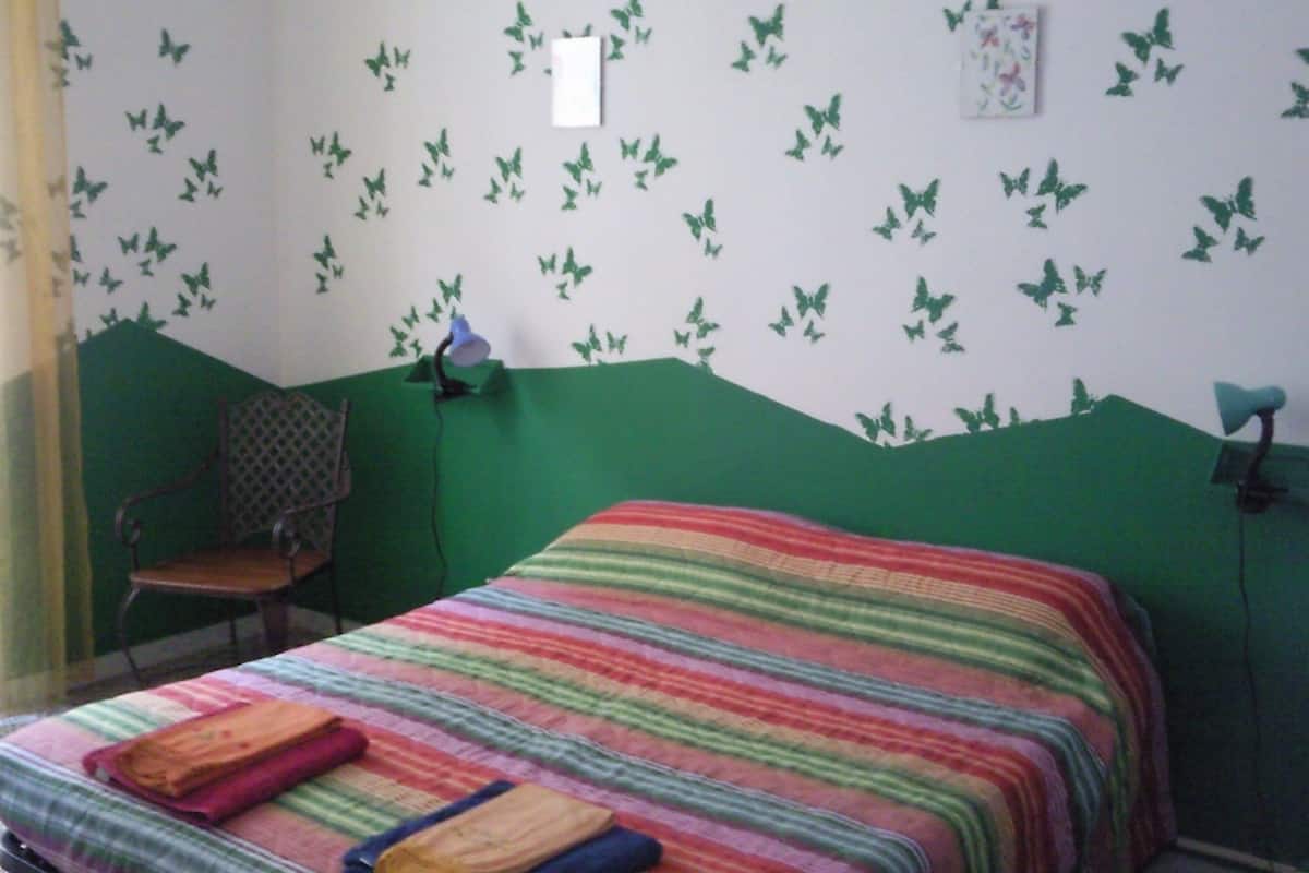A bedroom with a bed, a chair, and butterfly wall decals.