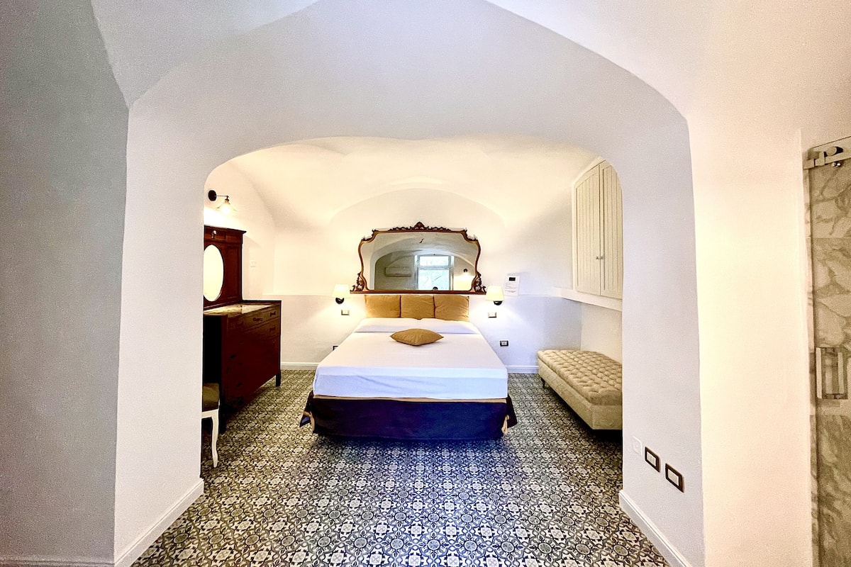 Un dormitorio con cama, cómoda, espejo y suelo estampado.