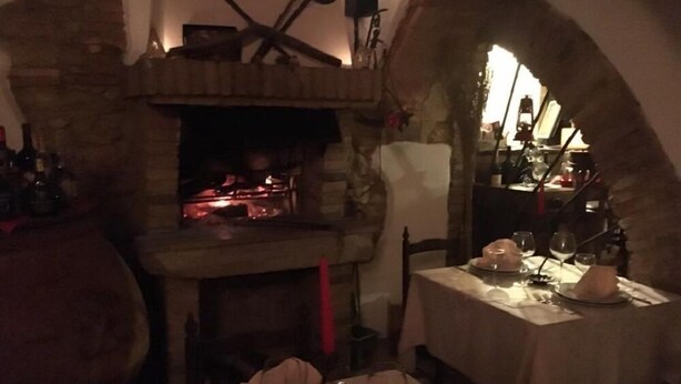 A rustic dining area with a stone fireplace, wooden furniture, and a table set for two. - Hotel il Malandrone (Castellina Marittima)