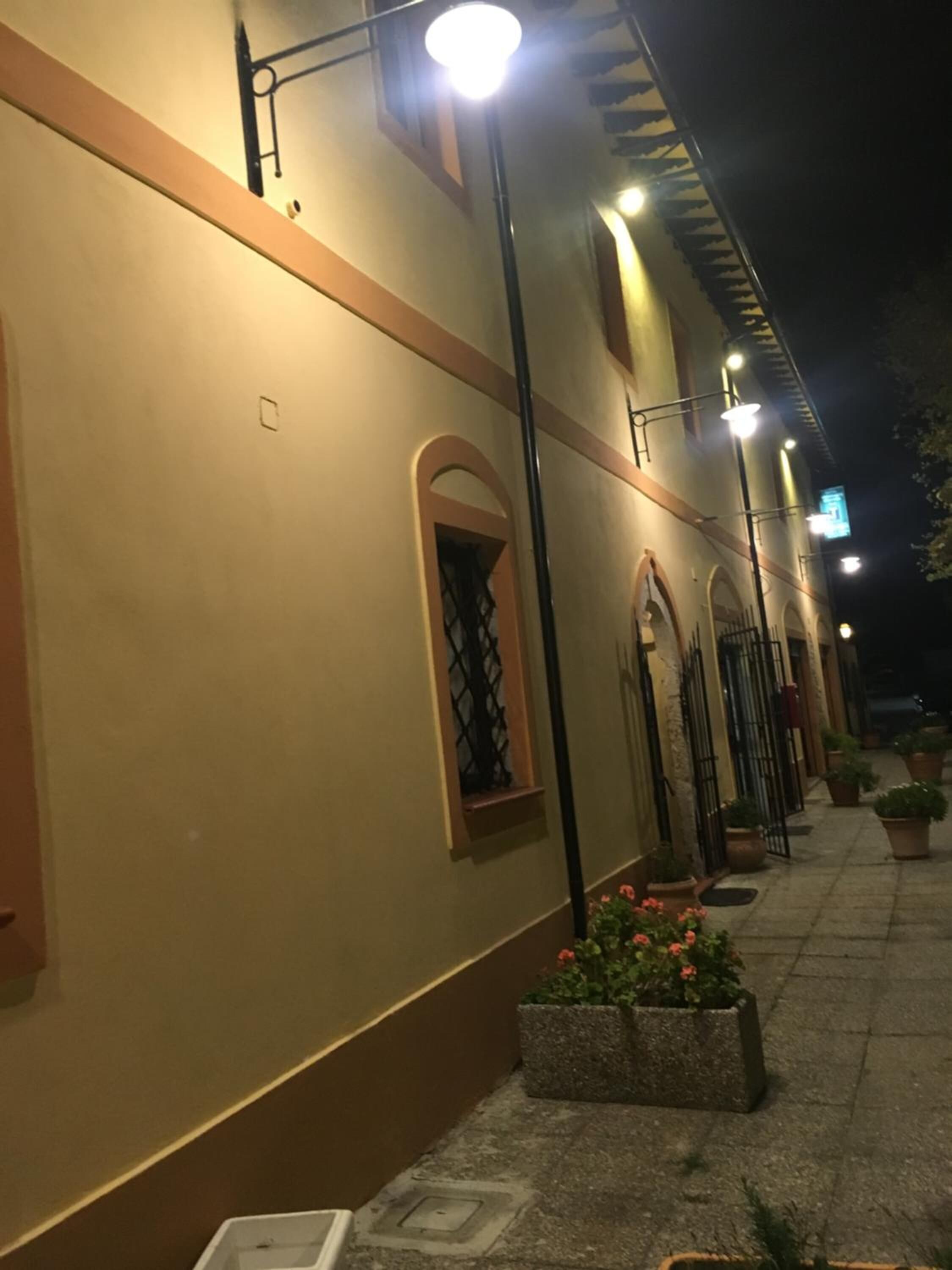 Ein Gebäude mit einer beige farbenen Fassade, gewölbten Fenstern und einem gefliesten Weg.