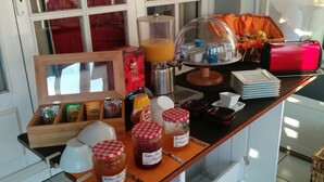 A breakfast buffet setup with various food items, condiments, and a coffee machine. - Hôtel Araur (Agde)