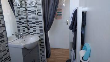 A bathroom with a sink, two hair dryers, a towel rack, and a door with a poster.