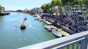 A riverside promenade with boats, spectators, and buildings along the water.