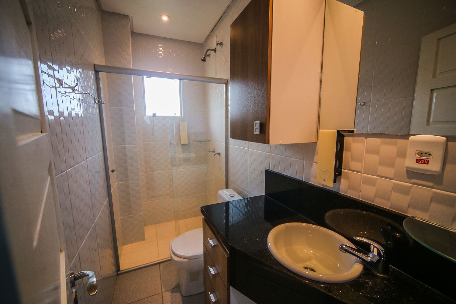 Une salle de bain moderne avec une douche à parois de verre, des toilettes, un lavabo avec un miroir et un porte-serviettes.