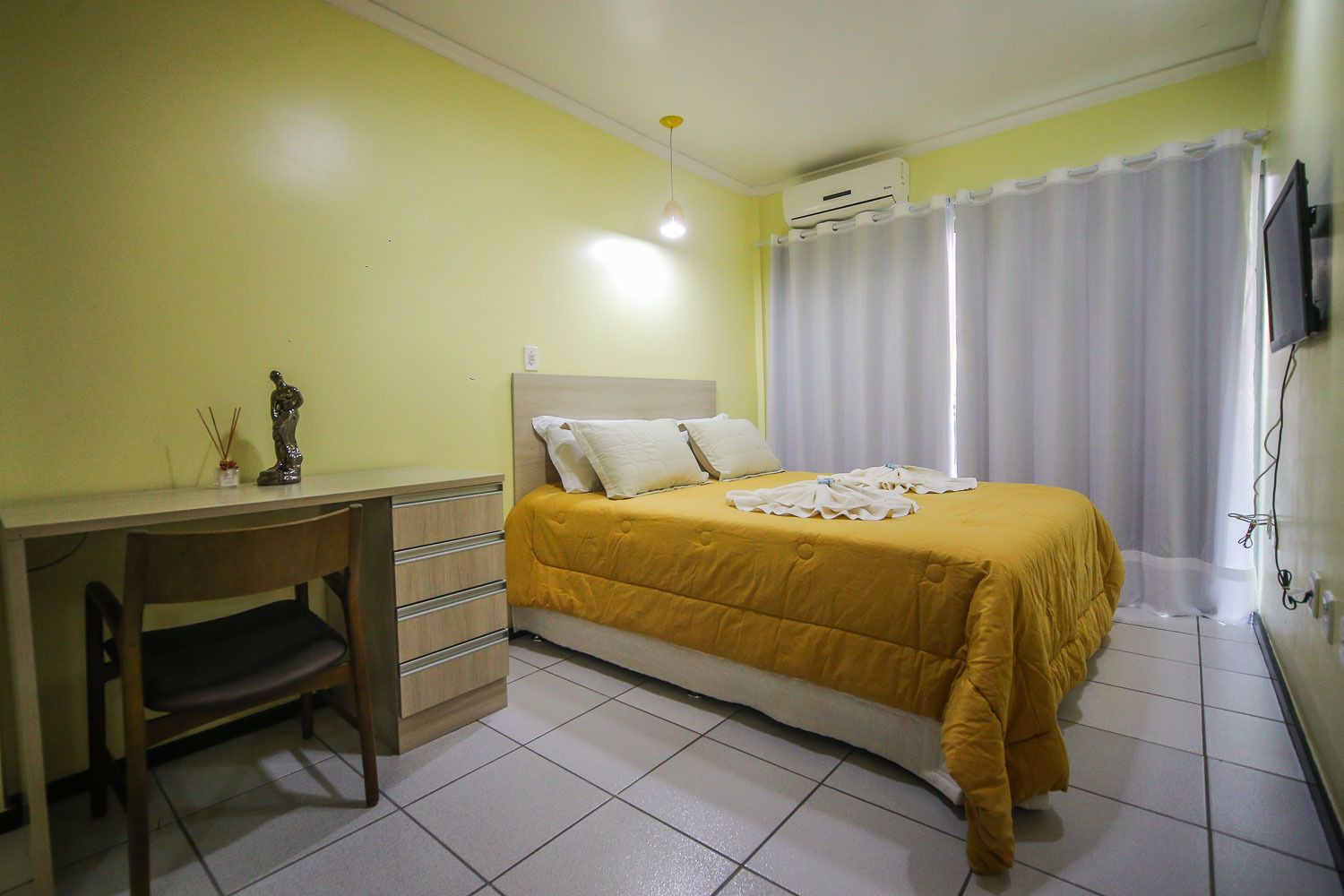 Een slaapkamer met een bed, een bureau en een stoel.