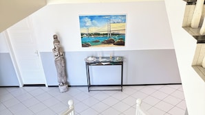 A staircase with white railings and black steps, leading to a landing with a painting of a bridge and a statue. - Hotel Pousada Laguna Rosa (Imbituba)