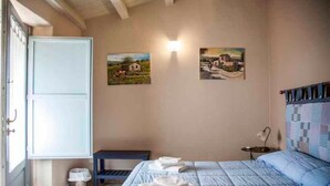 A bedroom with a bed, a bedside table, a lamp, and two paintings on the wall. - Avola Antica (Avola)