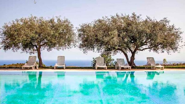 A pool with clear blue water, surrounded by lounge chairs and two large trees. - Avola Antica (Avola)