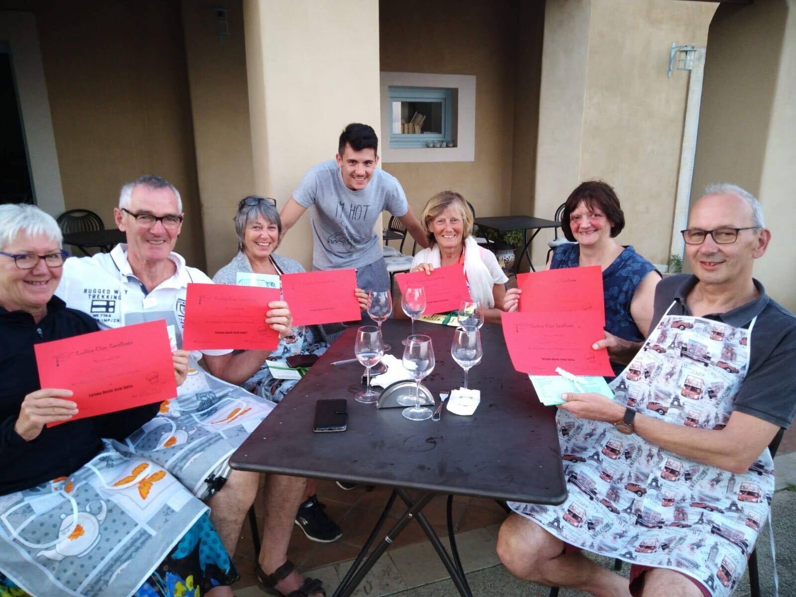 A group of people seated around a table with certificates, glasses, and a smartphone on it.