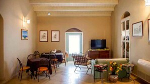 A spacious living room with a dining area, a television, and a sofa. - Avola Antica (Avola)