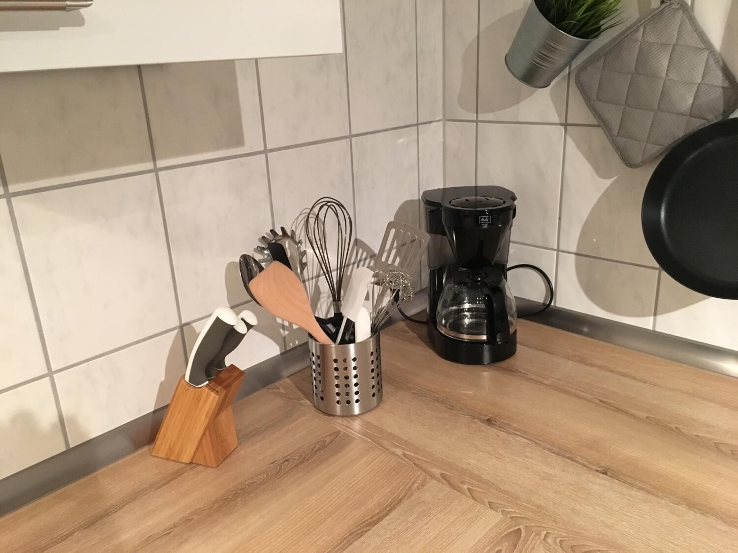 Cozinha equipada com cafeteira, utensílios e uma planta.