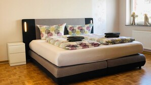 Un dormitorio con cama, mesita de noche, ventana con vistas y radiador.