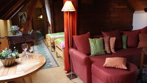 A cozy room with a red sofa, a wooden table with a vase of flowers, and a lamp. - Hotel zum Ginkgobaum (Stadtilm)