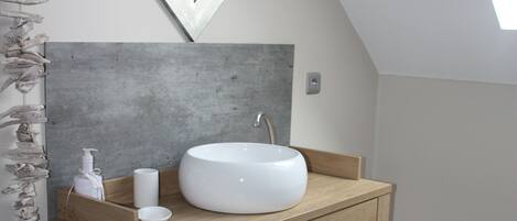 Un baño con tocador de madera, lavabo blanco y espejo.