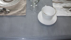 A breakfast table set with plates, cutlery, glasses, and a basket of croissants. - Comme un Rêve (Doignies)