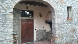 A stone building with a wooden door and an arched entrance. - Latera B&B (Barberino di Mugello)