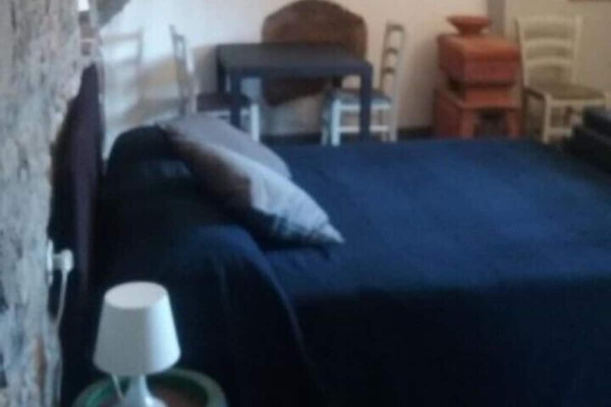 Makuuhuoneessa on sänky, pieni pöytä, tuoli ja lamppu.