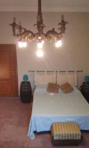 A bedroom with a bed, a chandelier, two bedside tables, and a wooden door. - Latera B&B (Barberino di Mugello)