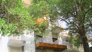 Un immeuble résidentiel à plusieurs étages, doté de balcons, d’une entrée sécurisée et de voitures garées.