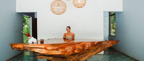 Un interior moderno con una mesa de centro de madera única, suelo de patrón geométrico y lámparas de mimbre colgantes.