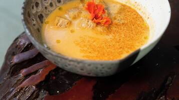 A bowl of soup with a flower garnish on a textured surface.
