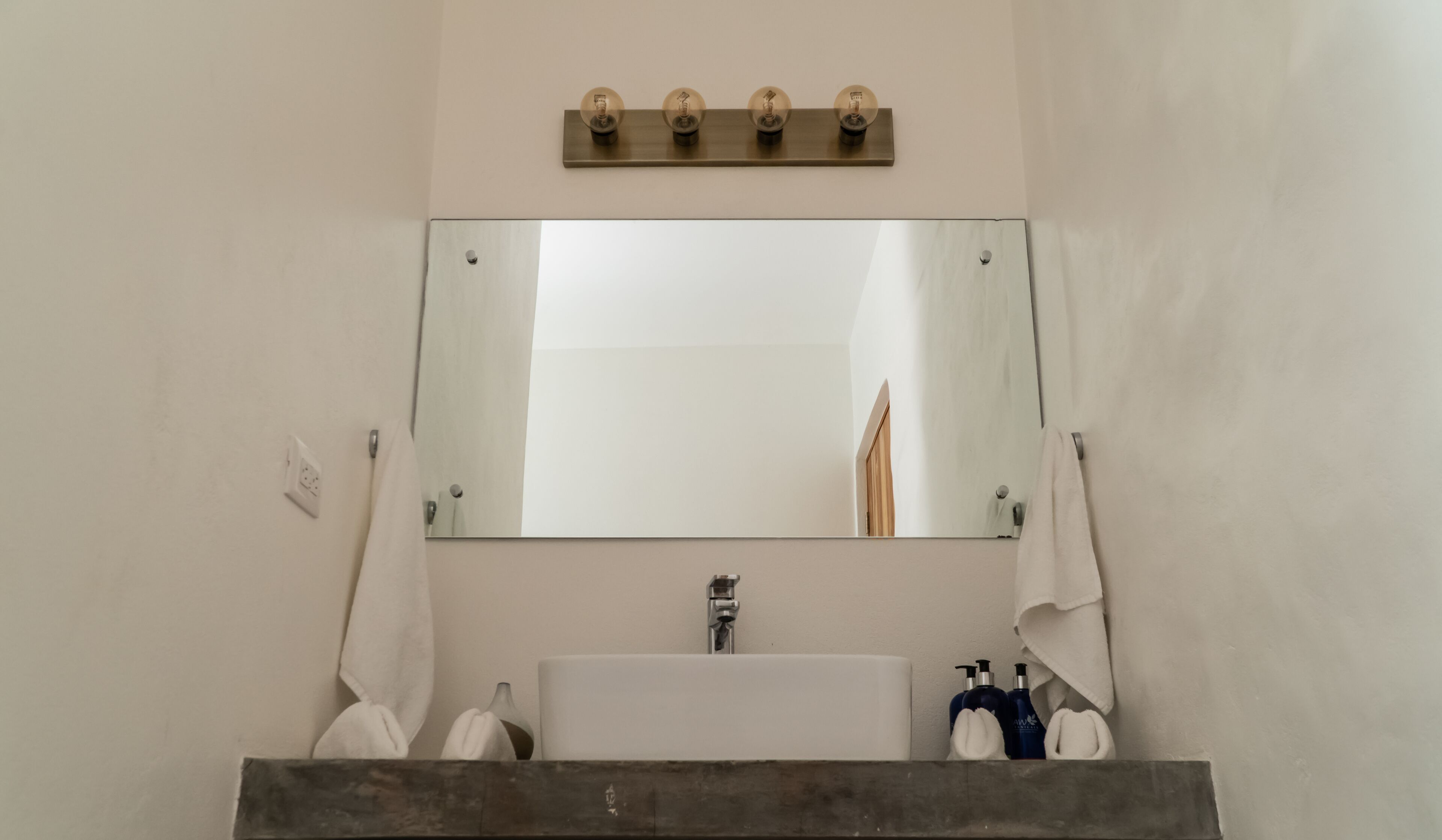Ein Badezimmer mit einem großen Spiegel, einem Waschbecken und zwei Handtüchern, die an der Wand hängen.