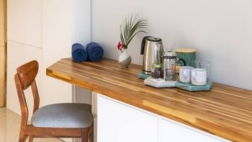 A kitchen counter with a coffee maker, a vase with a plant, and rolled towels.