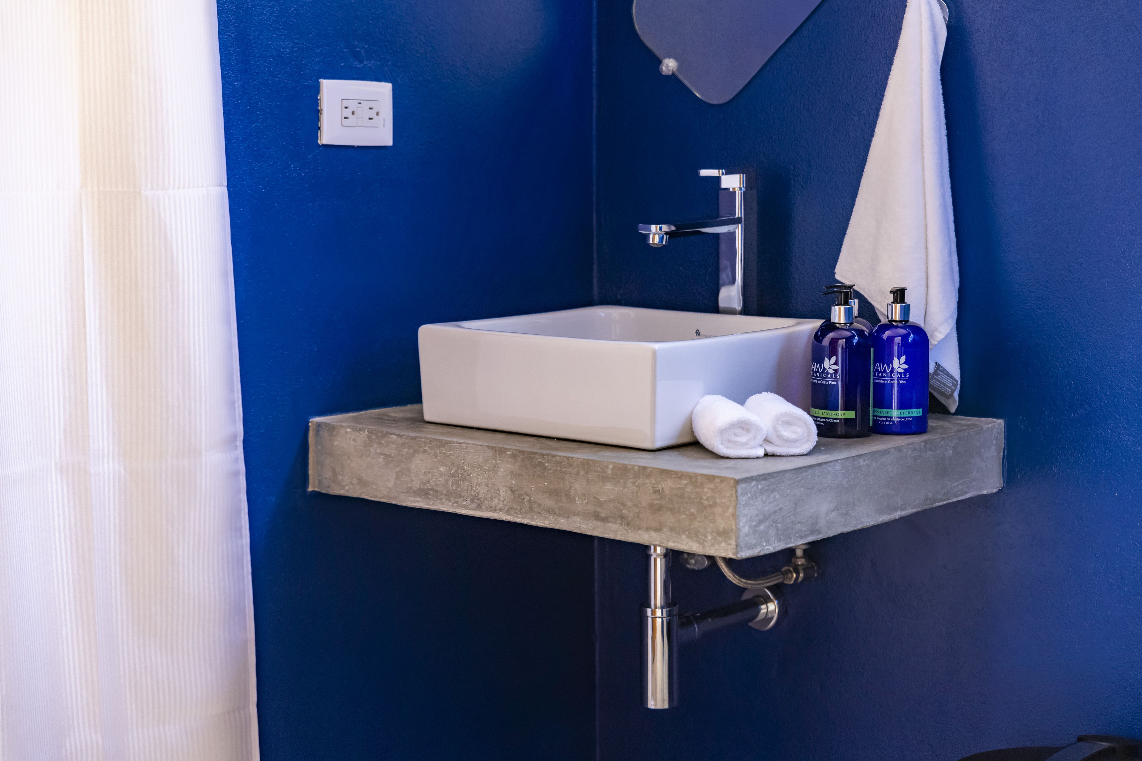 A bathroom with a white sink, two blue bottles, and a white towel on a gray countertop.