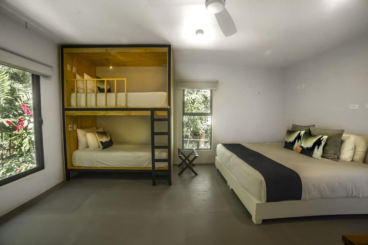 Quarto com uma cama de solteiro, uma cama de casal e uma escrivaninha.