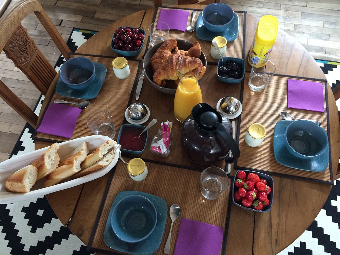 Et morgenbord med croissanter, jordbær og en kande appelsinjuice.
