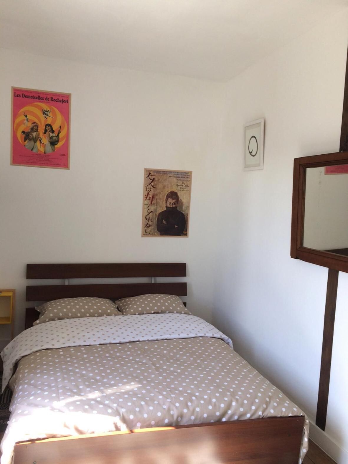 A bedroom with a bed, a wooden headboard, a poster on the wall, and a framed picture.