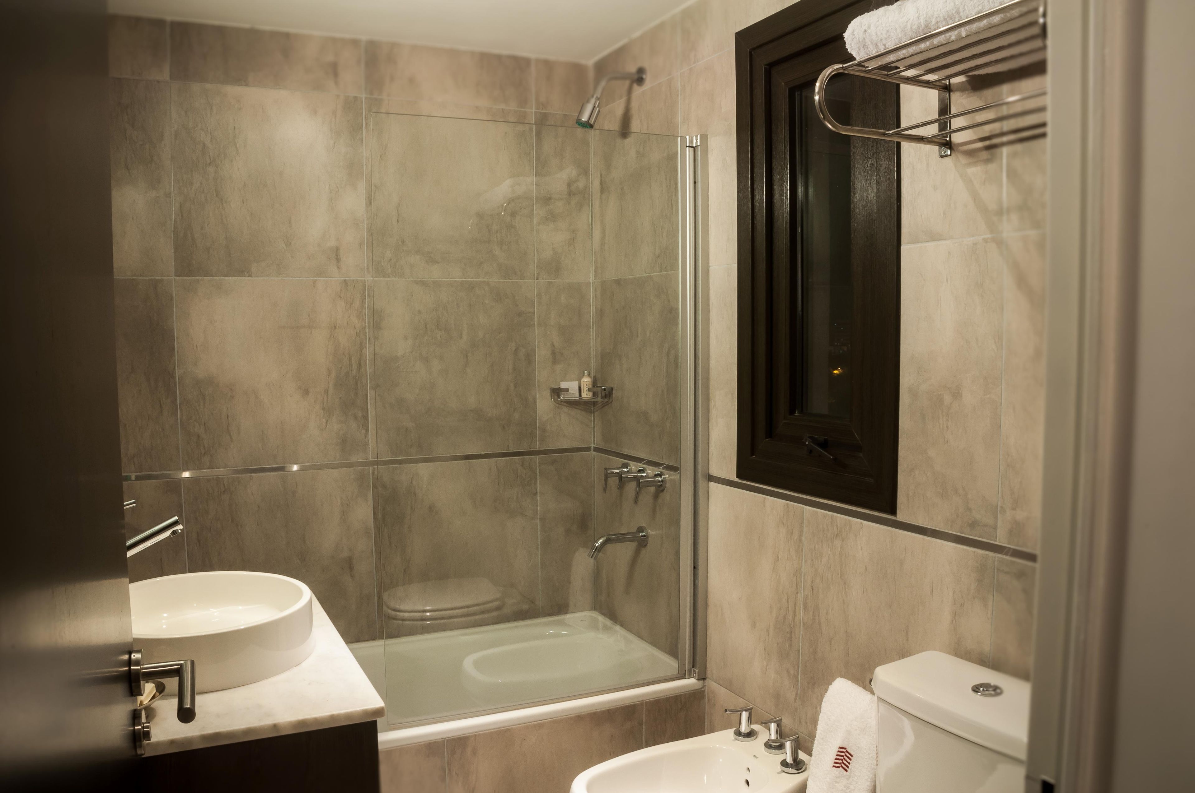 Un baño moderno con ducha de vidrio, una bañera independiente y un inodoro.