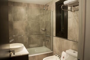 Un baño moderno con ducha de vidrio, una bañera independiente y un inodoro.