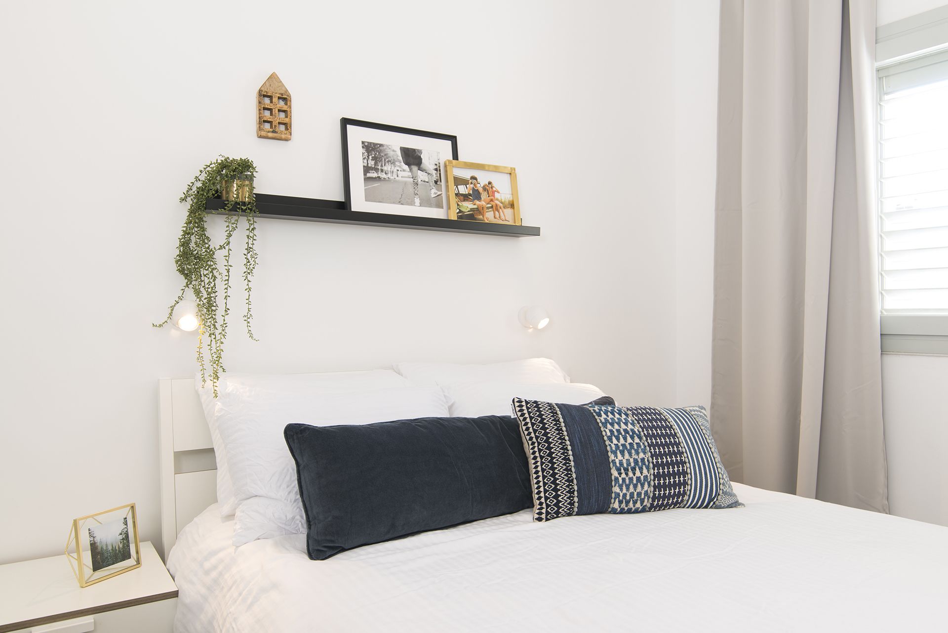 Quarto bem arrumado com cama, mesas de cabeceira e prateleiras na parede.