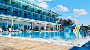 Un resort con piscina, sillas de descanso y un tobogán de agua.
