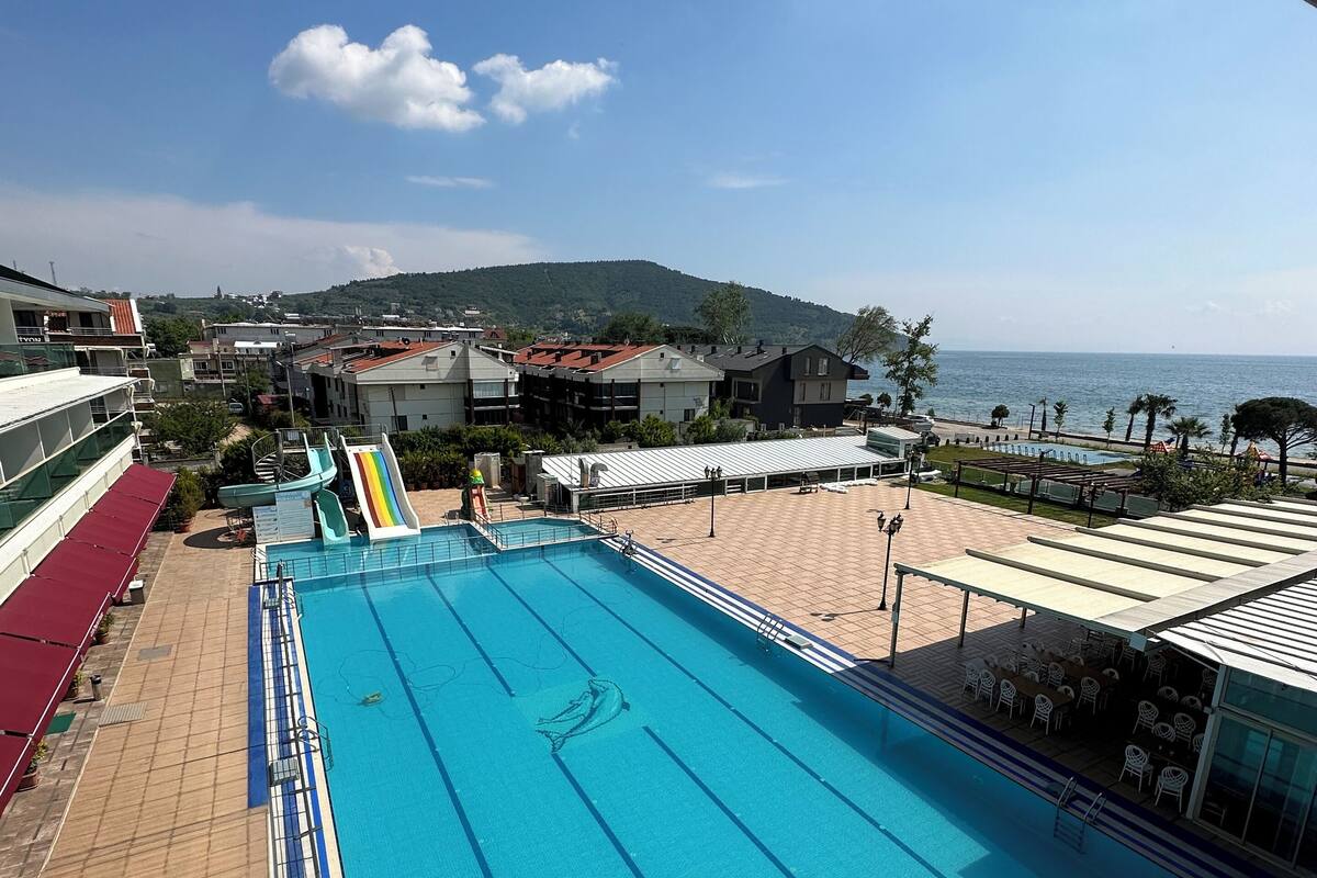 A swimming pool with a view of the sea and buildings in the background.
