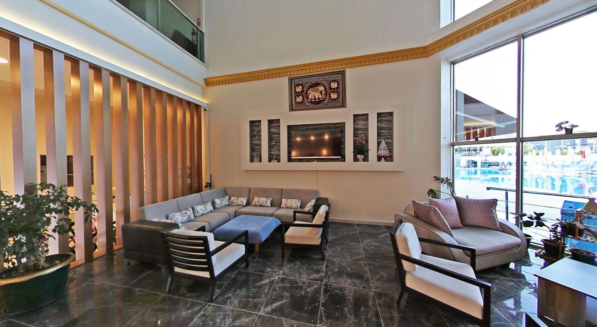 A spacious living area with a large sofa, a smaller sofa, and a coffee table. There is a fireplace with a mantel and wall-mounted artwork above it.
