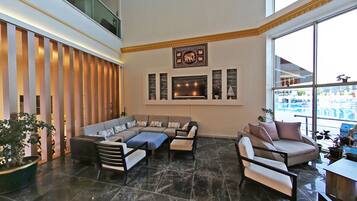A spacious living area with a large sofa, a smaller sofa, and a coffee table. There is a fireplace with a mantel and wall-mounted artwork above it.