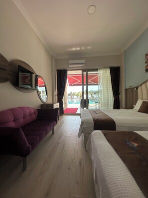 A hotel room with a sofa, two beds, a TV mounted on the wall, and a view of the outside. - Cetin Prestige Resort (Erdek)