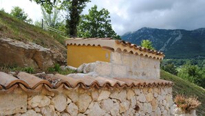 A stone building with a yellow facade and a tiled roof, surrounded by a mountainous landscape. - B&B Pascale (Cusano Mutri)