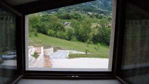A window with a view of a green landscape, a stone wall, and a road. - B&B Pascale (Cusano Mutri)