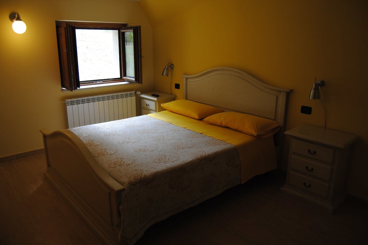 A bedroom with a bed, bedside tables, a window, and a radiator.