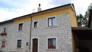 A stone building with a yellow facade, multiple windows, and a door. - B&B Pascale (Cusano Mutri)