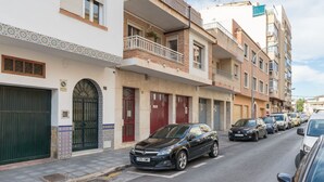 A street view of a residential area with multi-story buildings, parked cars, and a clear sky. - Rafaela Guest House (Málaga)